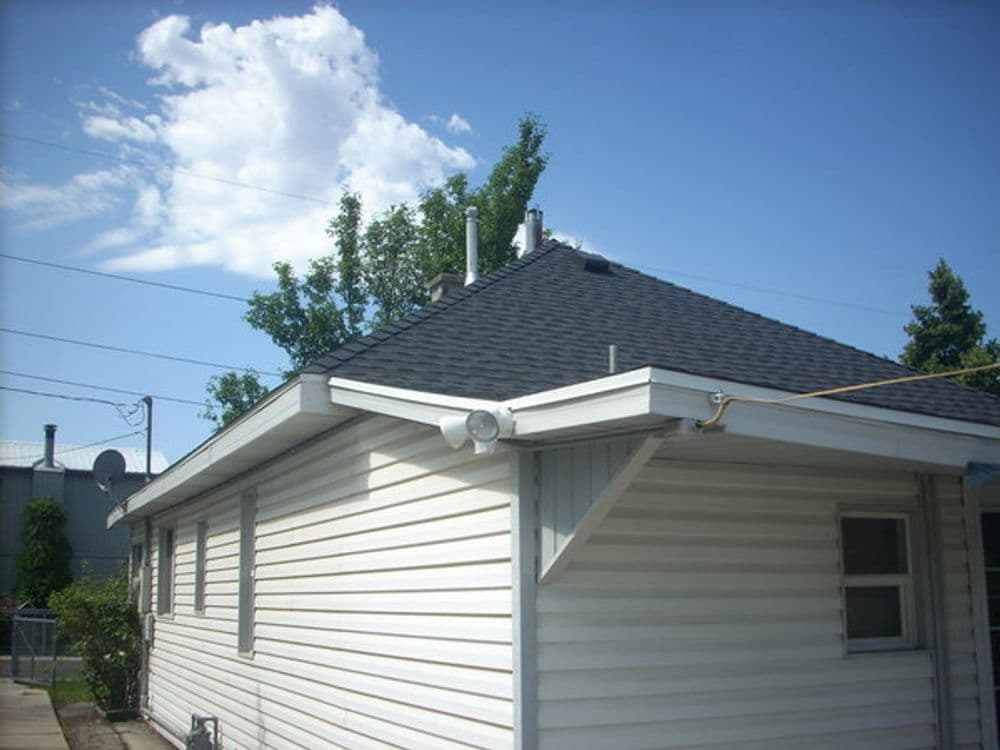 Back view of a single-story house with a sloped roof and clear blue sky.
