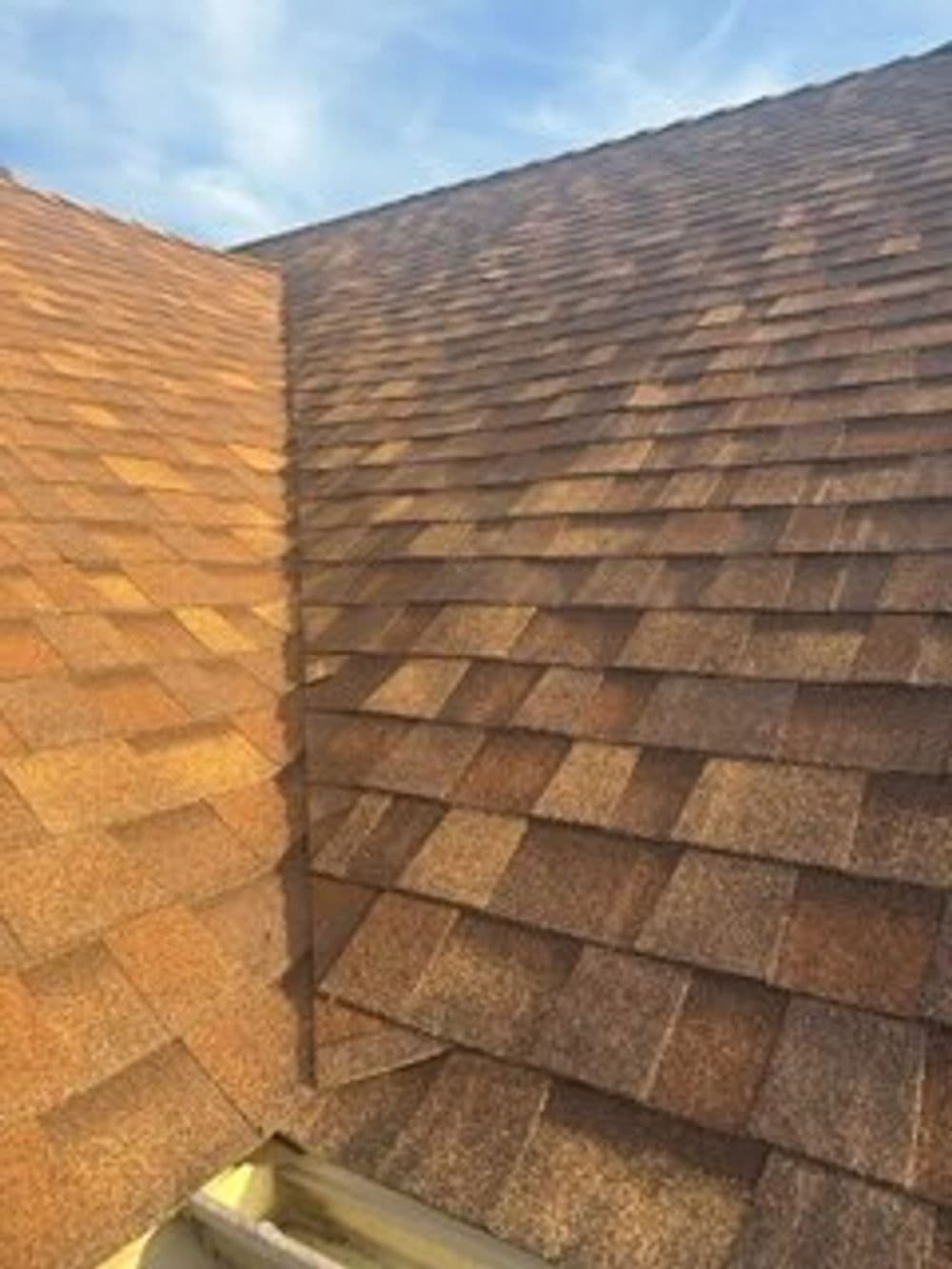 Newly installed asphalt shingle roof with a warm brown color under a clear blue sky.