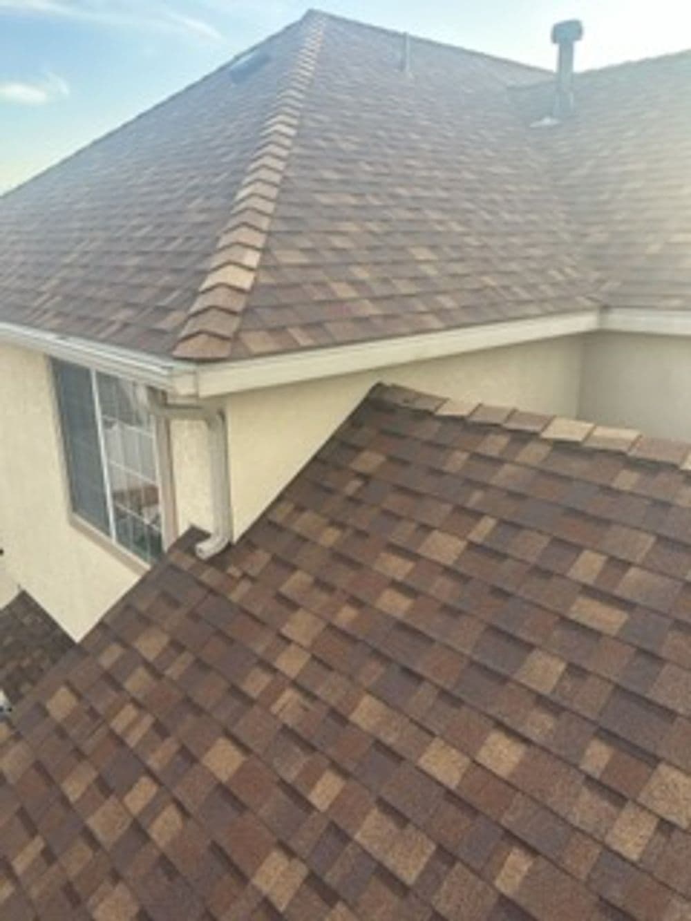 Roofing shingles on a house, showcasing a well-maintained brown and tan pattern.